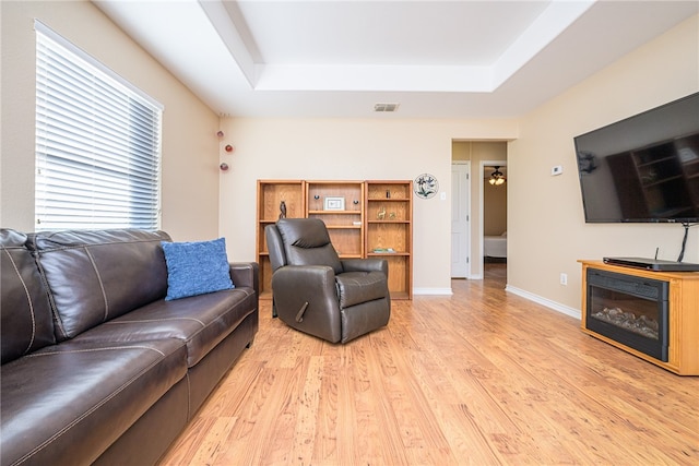 living room with a raised ceiling and light hardwood / wood-style flooring