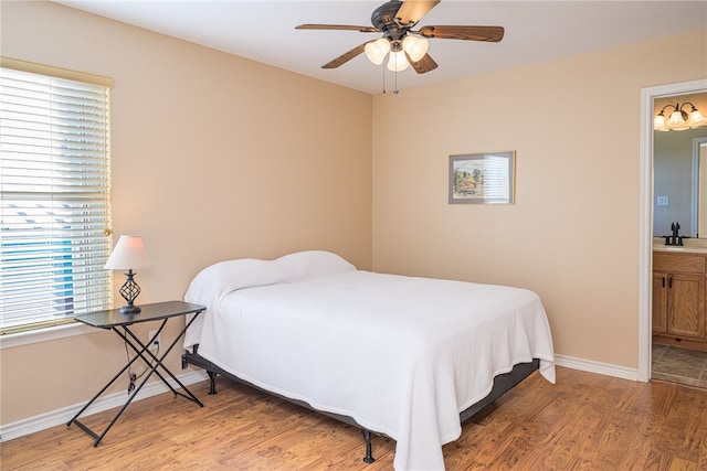 bedroom featuring light wood-type flooring, connected bathroom, ceiling fan, and sink