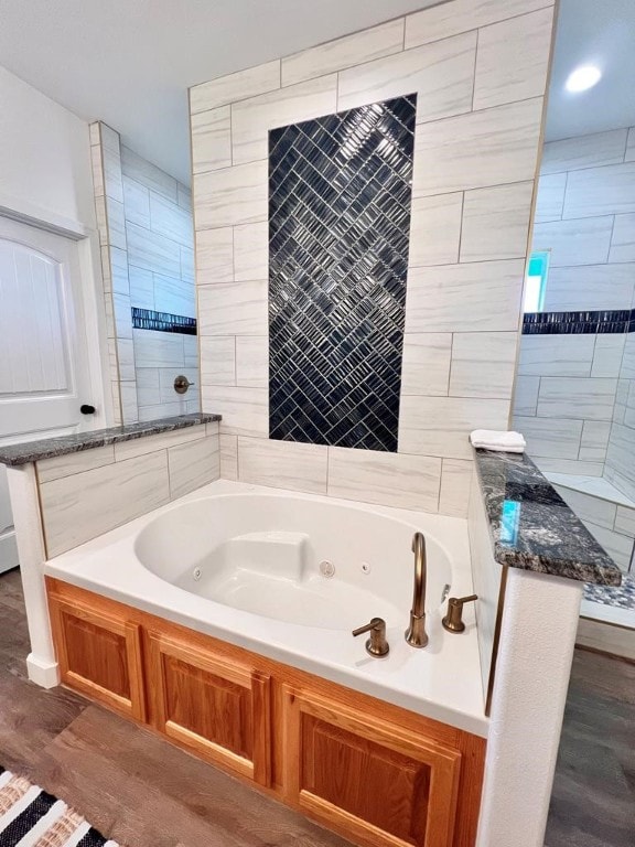 bathroom with hardwood / wood-style flooring and a tub to relax in