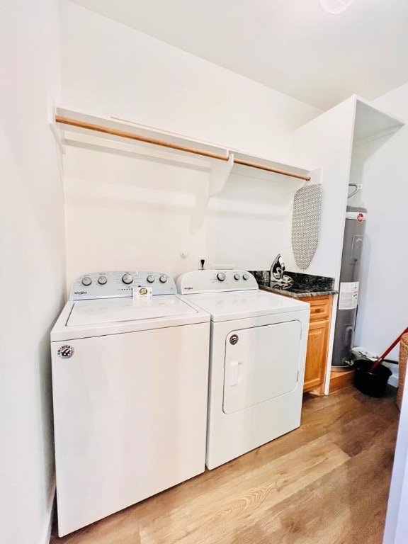 clothes washing area featuring light wood-type flooring, cabinets, washer and dryer, and electric water heater