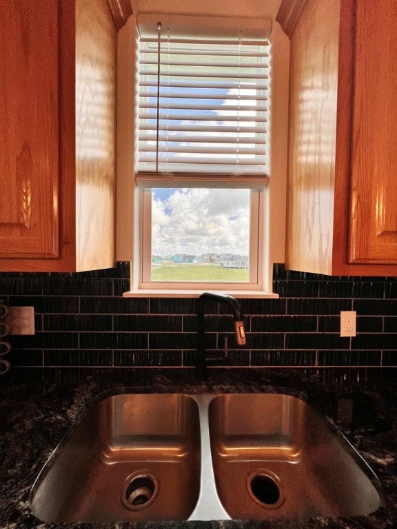 details with dark stone counters, backsplash, and sink