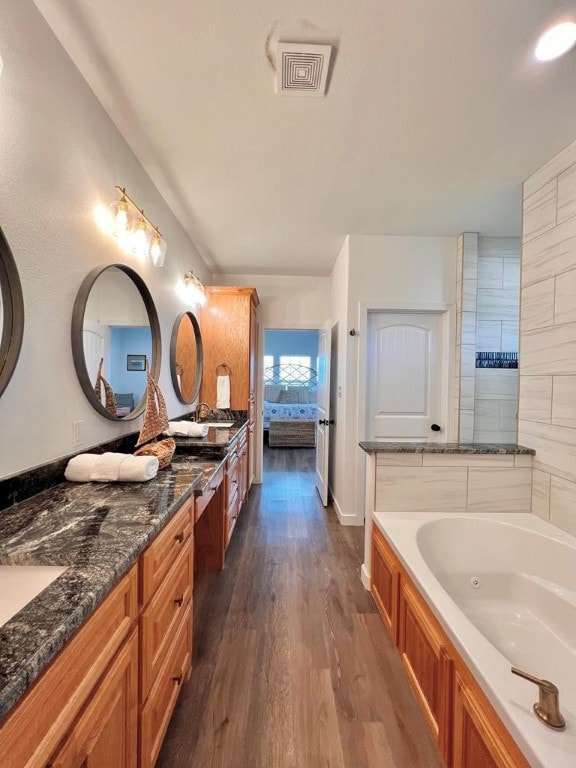 bathroom with hardwood / wood-style flooring, a tub to relax in, and vanity