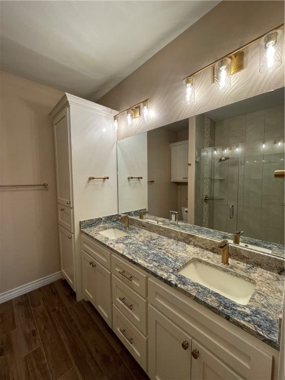 bathroom featuring toilet, vanity, hardwood / wood-style floors, and a shower with door