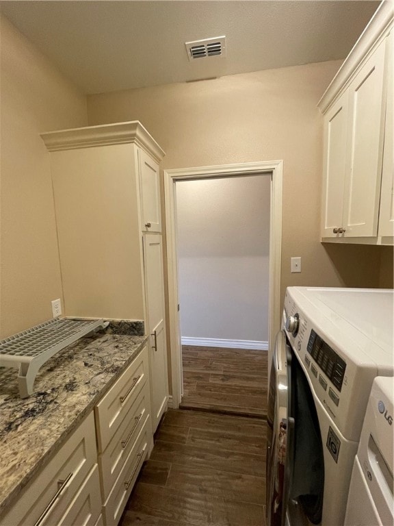 clothes washing area featuring cabinets, dark hardwood / wood-style floors, and washer and clothes dryer