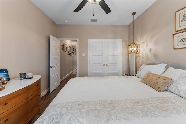 bedroom with ceiling fan with notable chandelier, a closet, and dark hardwood / wood-style flooring