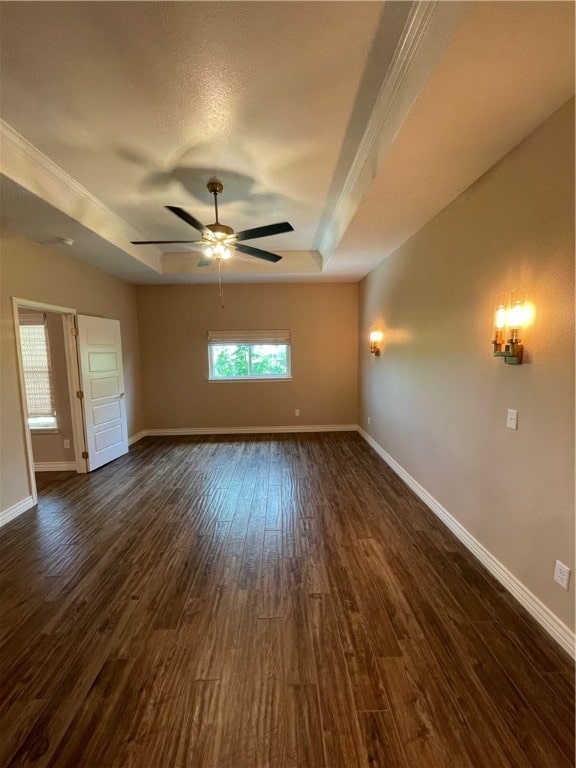 empty room with ceiling fan, a textured ceiling, dark hardwood / wood-style floors, and a raised ceiling