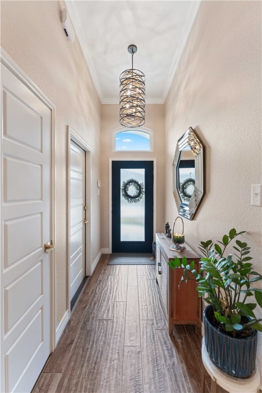 doorway featuring an inviting chandelier, dark hardwood / wood-style flooring, and ornamental molding