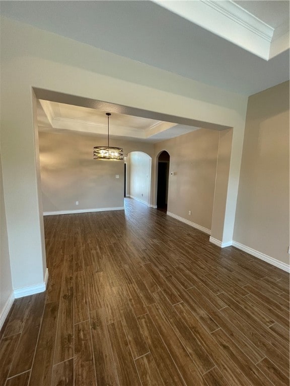 unfurnished room featuring dark hardwood / wood-style flooring, ornamental molding, and a raised ceiling