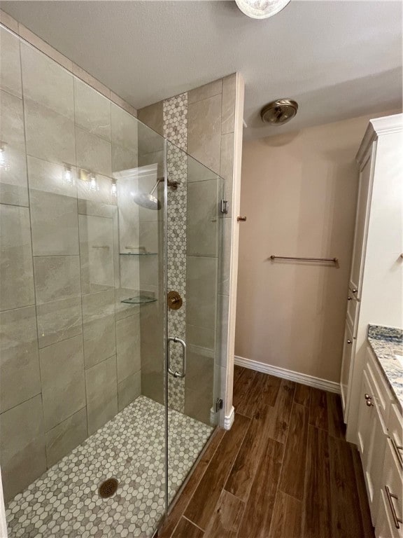 bathroom featuring vanity, hardwood / wood-style flooring, and a shower with door