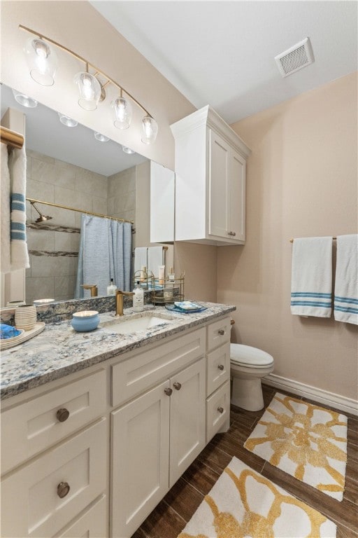 bathroom with walk in shower, vanity, hardwood / wood-style flooring, and toilet