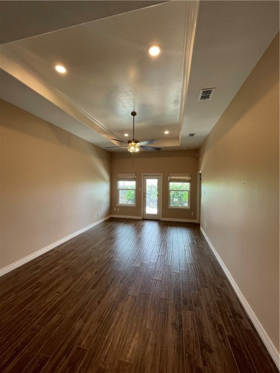 unfurnished living room featuring ceiling fan, dark hardwood / wood-style floors, and a raised ceiling