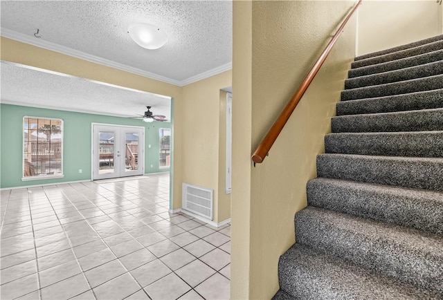 stairway featuring crown molding, a textured ceiling, tile patterned floors, ceiling fan, and visible vents