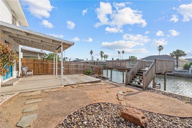 view of patio with a deck with water view, stairs, and fence