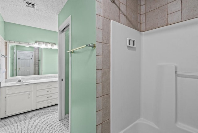 bathroom with tile patterned floors, a textured ceiling, vanity, walk in shower, and visible vents