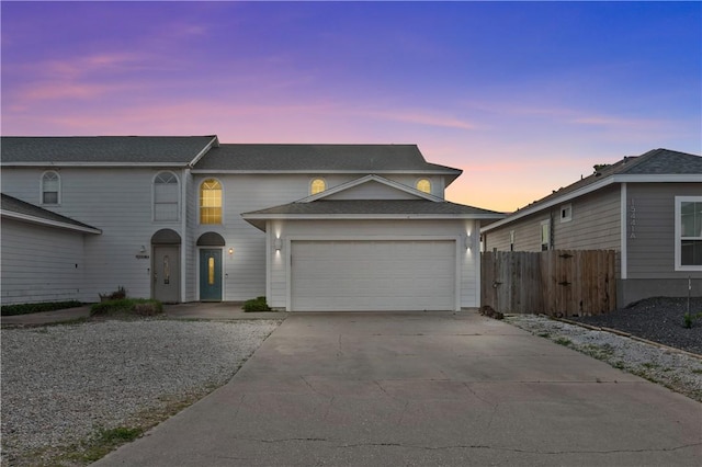 traditional home with an attached garage, fence, and driveway