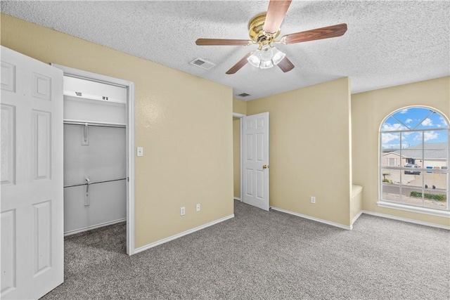 unfurnished bedroom featuring a spacious closet, carpet floors, a textured ceiling, and visible vents