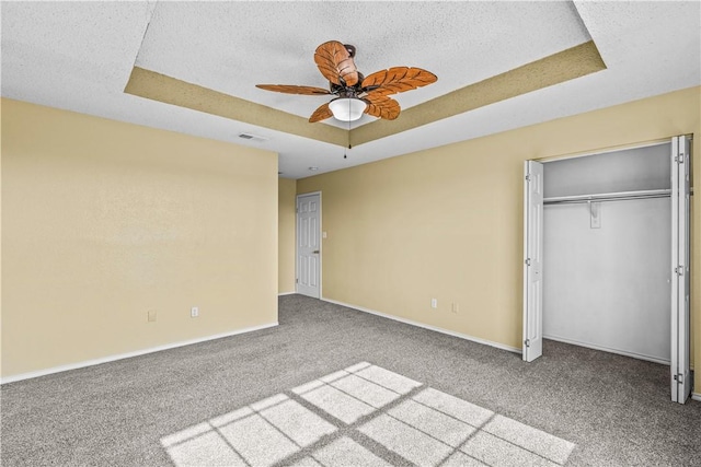 unfurnished bedroom featuring visible vents, carpet flooring, a textured ceiling, and a raised ceiling