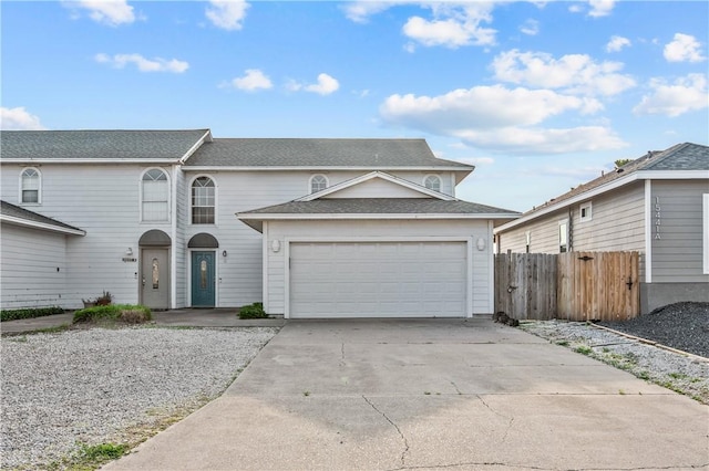 view of front of property with an attached garage, concrete driveway, fence, and roof with shingles