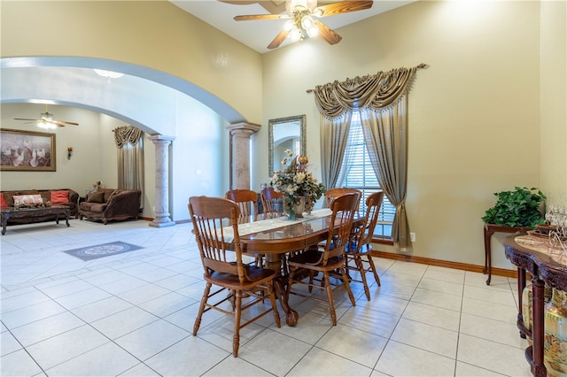 tiled dining space with ceiling fan and decorative columns