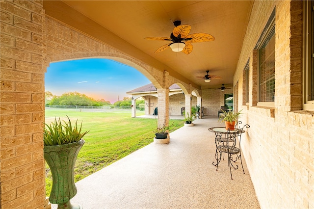 patio terrace at dusk with ceiling fan and a lawn