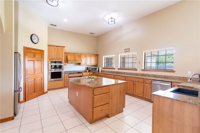 kitchen featuring a towering ceiling, appliances with stainless steel finishes, sink, kitchen peninsula, and a center island