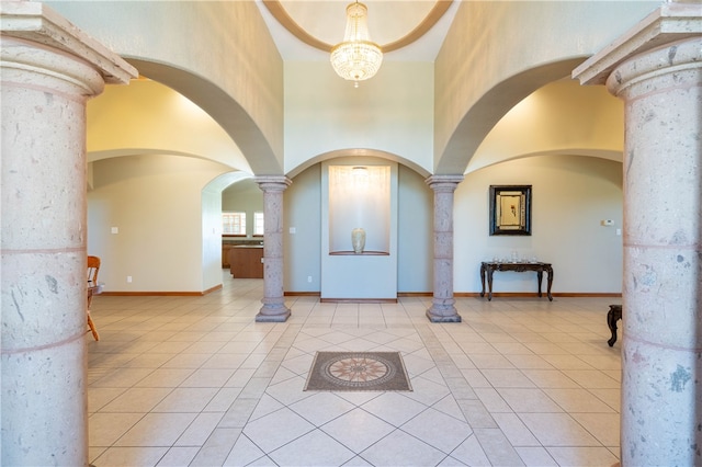 entryway featuring decorative columns, light tile patterned flooring, and a towering ceiling