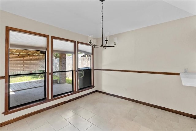 spare room with an inviting chandelier and baseboards