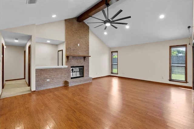 unfurnished living room featuring a fireplace, ceiling fan, wood finished floors, high vaulted ceiling, and beamed ceiling