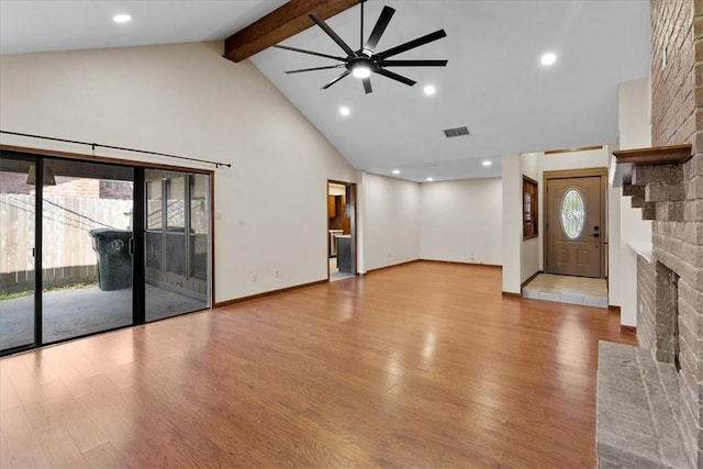 unfurnished living room featuring visible vents, wood finished floors, beamed ceiling, a fireplace, and high vaulted ceiling