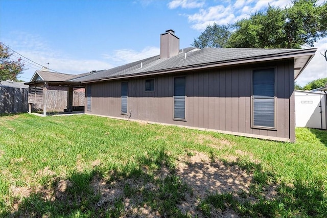 rear view of property with a yard, a chimney, and fence