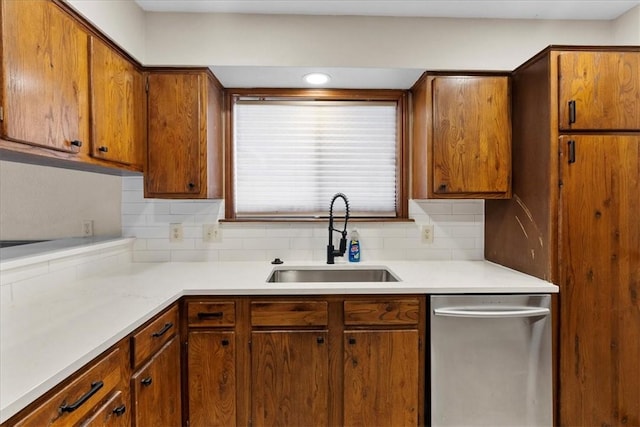 kitchen featuring tasteful backsplash, light countertops, a sink, and dishwasher