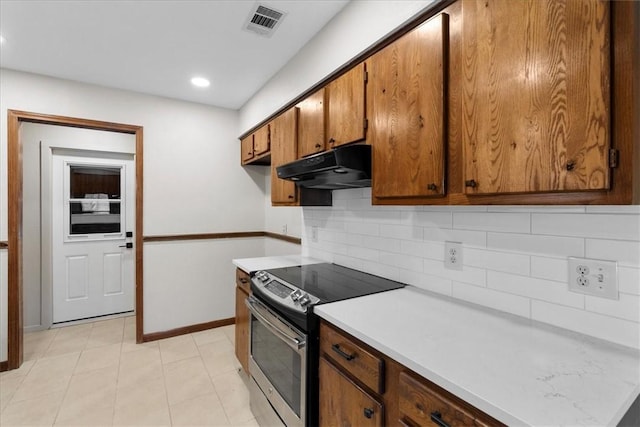 kitchen featuring tasteful backsplash, visible vents, electric stove, brown cabinets, and under cabinet range hood