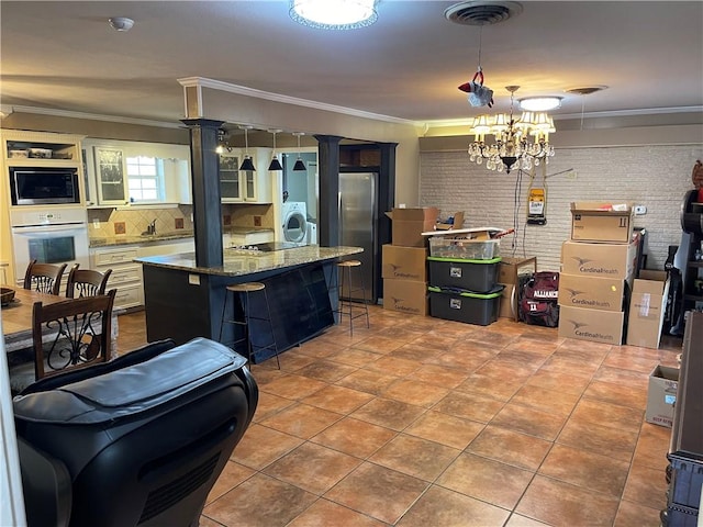 kitchen with brick wall, built in microwave, freestanding refrigerator, ornamental molding, and white oven