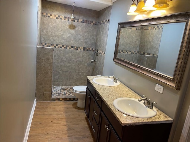 bathroom featuring wood finished floors, toilet, walk in shower, and a sink