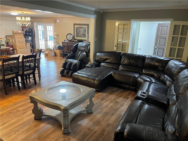 living area with crown molding, a notable chandelier, wood finished floors, and french doors