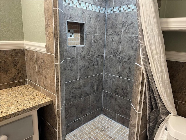 full bath featuring a shower stall, tile walls, a wainscoted wall, a textured wall, and vanity