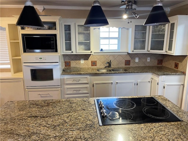 kitchen featuring oven, ornamental molding, a sink, built in microwave, and black electric stovetop