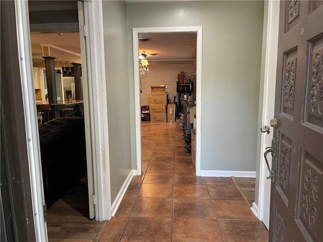 corridor featuring dark tile patterned flooring, baseboards, and ornamental molding