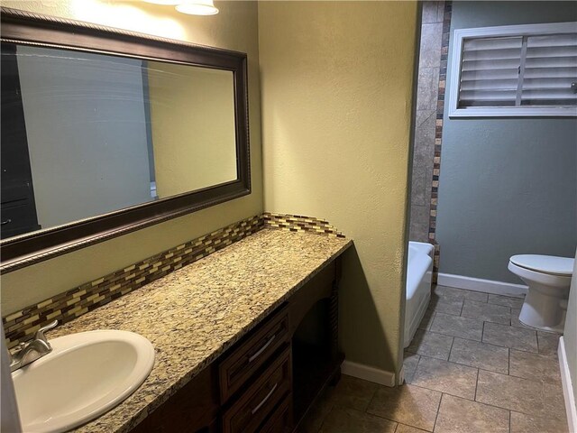 full bathroom featuring vanity, toilet, tasteful backsplash, and baseboards