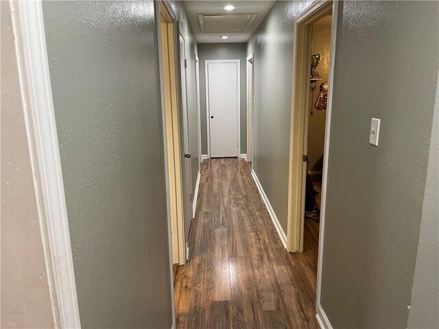 hallway featuring dark wood-style floors, baseboards, and a textured wall