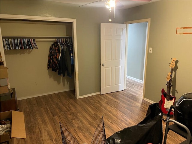 bedroom featuring a closet, baseboards, wood finished floors, and a ceiling fan