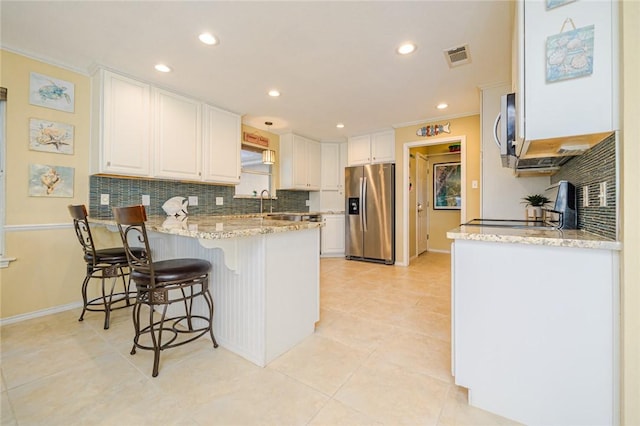 913 Pompano Dr, Aransas Pass, TX 78336 - kitchen featuring stainless steel appliances, a peninsula, decorative backsplash, white cabinetry, and light stone countertops