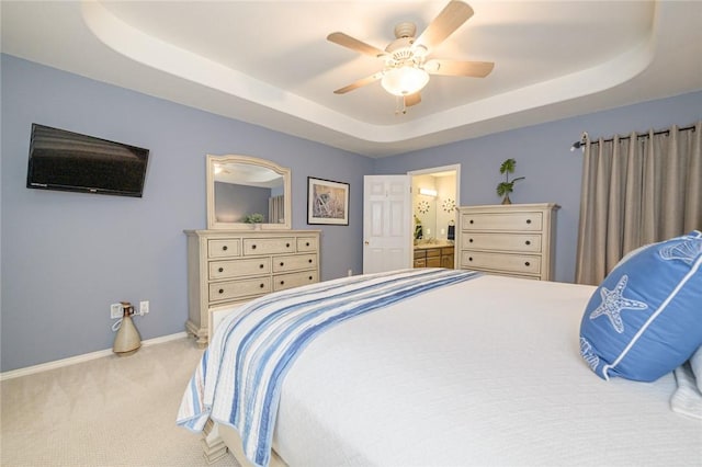 913 Pompano Dr, Aransas Pass, TX 78336 - carpeted bedroom with a tray ceiling, baseboards, ceiling fan, and ensuite bath