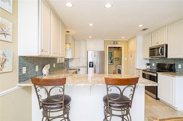 913 Pompano Dr, Aransas Pass, TX 78336 - kitchen with appliances with stainless steel finishes, a peninsula, a sink, light stone countertops, and tasteful backsplash