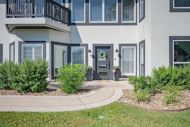 property entrance featuring stucco siding and a balcony