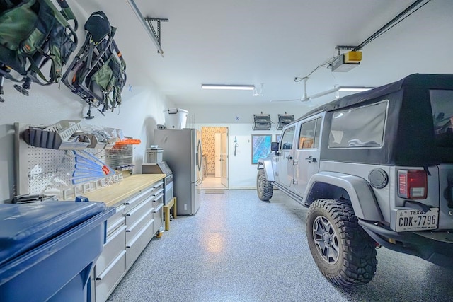 garage featuring freestanding refrigerator and a garage door opener