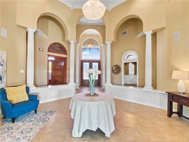 interior space featuring decorative columns, a high ceiling, light tile patterned floors, and a notable chandelier