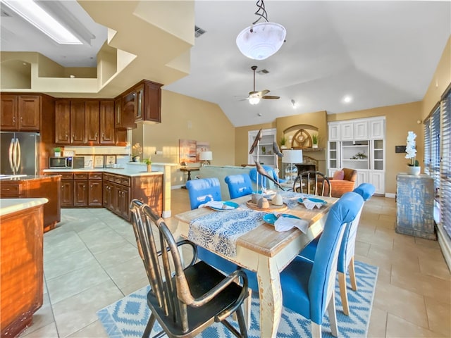 tiled dining area featuring ceiling fan, built in features, and lofted ceiling