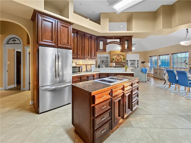 kitchen with a center island, appliances with stainless steel finishes, light tile patterned floors, and a towering ceiling