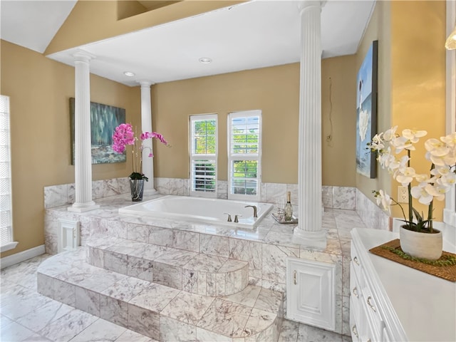 bathroom with decorative columns and a relaxing tiled tub